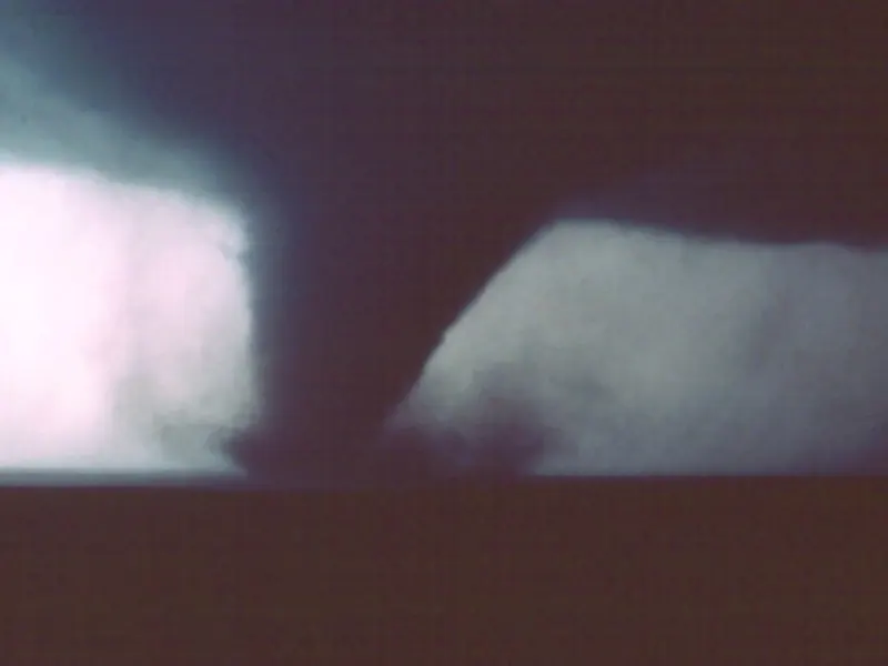 A tornado touching down beyond a small Texas town, under a dark storm cloud