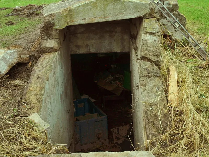 The wooden doorway of an old underground storm cellar set into a grassy mound
