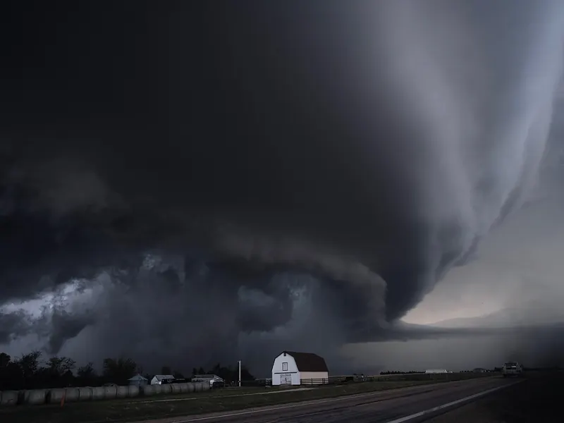 A huge, layered thunderstorm cloud towering over flat land